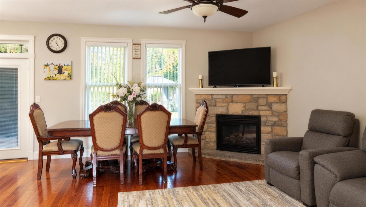 The living and dining room, with a wooden dining table for six, a stone fireplace and two recliners.